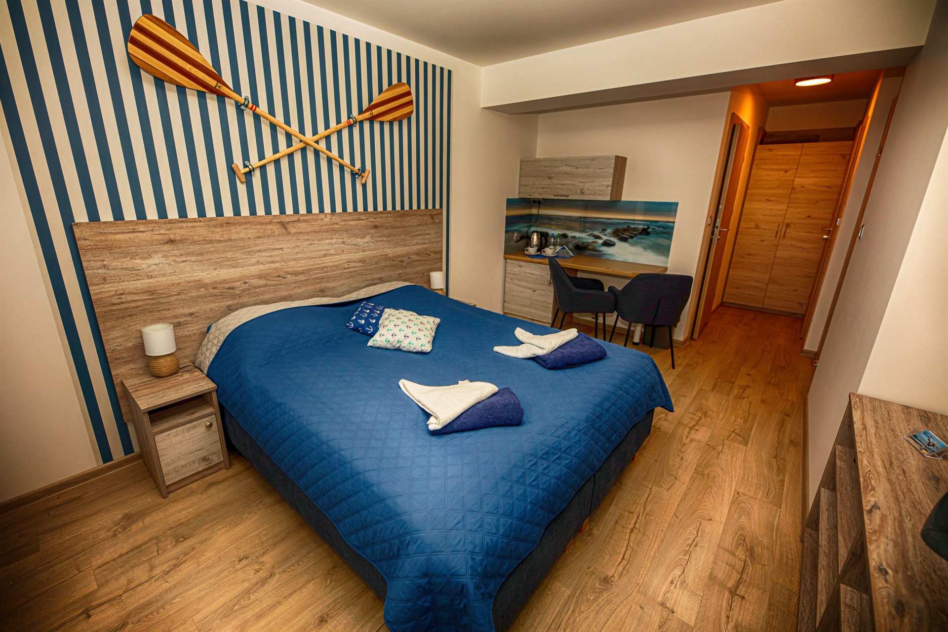 Sypialnia z niebieską narzutą, skrzyżowane drewniane wiosła na niebiesko-białej ścianie
